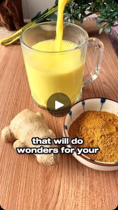 a cup filled with yellow liquid next to a bowl full of tumerics and ginger