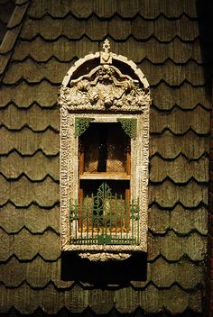 an old window on the side of a building with green roofing and decorative ironwork