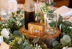 the table is set with vases and greenery on top of it, along with a wooden block that says five