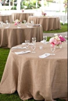 the tables are set up outside on the grass for an outdoor wedding reception with pink flowers and greenery