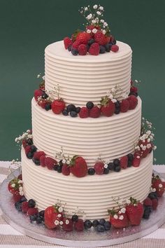 a triple layer cake with berries and blueberries on top