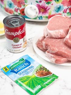 raw meat on a white plate next to a can of soup and some other ingredients