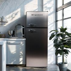 a metallic refrigerator in a kitchen next to a potted plant and window sill