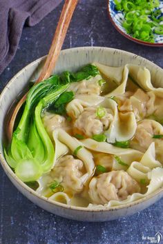 a bowl filled with dumplings and broccoli on top of a blue table