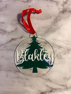 a glass ornament with the word bakey hanging from a red ribbon