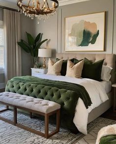 a bedroom with a large bed and green pillows on the headboard, along with a chandelier