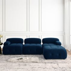 a blue couch sitting on top of a rug in front of a white wall and floor