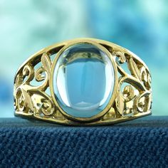 Enhance your style with this captivating vintage-inspired ring that exudes romance and sophistication. The delicate filigree work beautifully complements the smooth, oval cabochon blue topaz, creating an air of understated elegance. The warm, classic touch of yellow gold adds a timeless appeal, making this ring a perfect embodiment of feminine grace. Treat yourself to this graceful piece and experience a blend of vintage charm and contemporary allure. CHARACTERISTICS Status: Made to order Origin Vintage Topaz Ring, Classic Oval Filigree Ring With Intaglio, Luxury Round Topaz Ring With Filigree, Elegant Filigree Ring With Cabochon For Anniversary, Oval Cabochon Topaz Ring For Anniversary, Formal Oval Cabochon Topaz Ring, Formal Oval Topaz Ring With Filigree, Formal Oval Blue Topaz Filigree Ring, Anniversary Oval Cabochon Topaz Ring