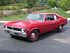 an old red car parked in a parking lot