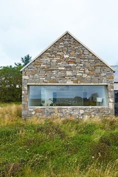 a stone building with a window in the front and grass on the other side outside