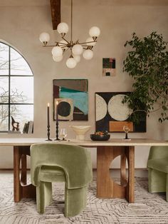 an elegant dining room with green chairs and art