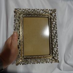 a person holding up a small gold frame