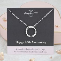 a card with a silver necklace on it next to a pink box and gold hearts