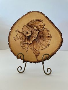 a decorative wooden plate with a fish on it's side and a metal stand