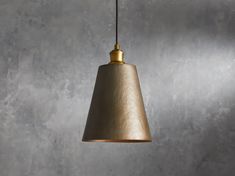 a light hanging from a ceiling in a room with concrete wall and flooring behind it