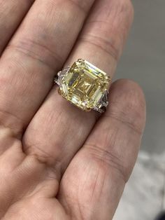 a yellow diamond is being held in someone's hand with it's fingers