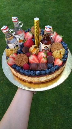 a person holding a cake on top of a metal platter with fruit and chocolate toppings