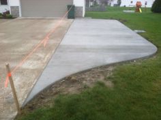 a concrete driveway is being constructed in front of a house with an orange tape on it