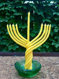 a green glass bowl with yellow candles in the shape of a menorah on it