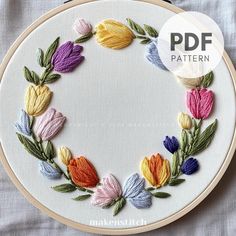 an embroidery project with flowers and leaves in the hoop on top of a white table cloth