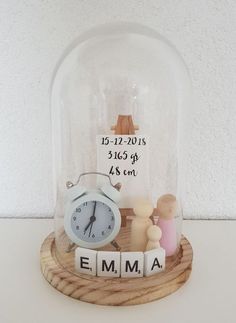 a snow globe with an alarm clock and wooden letters underneath it that spell out the word emma