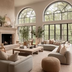 a living room filled with lots of furniture next to large windows and a fire place