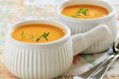 two white bowls filled with soup on top of a table