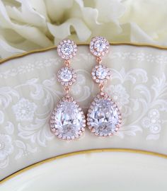 "Swarovski Pure Brilliance Cubic Zirconia rose gold bridal earrings feature pave framed rounds which dangle into a brilliant pear-shaped drop. These beautiful earrings are created in genuine Rose Gold plating and they're sure to look glamorous on brides looking for blush gold jewelry to accessorize their wedding gowns. Earrings measure 1-7/8\" Matching necklace: https://www.etsy.com/listing/273127374/bridal-backdrop-necklace-rose-gold-back?ref=shop_home_active_1 Matching bracelet: https://www.et Wedding Bridal Earrings In Rose Gold With Halo Design, Rose Gold Halo Bridal Earrings For Wedding, Rose Gold Bridal Drop Earrings With Elegant Design, Glamorous Rose Gold Dangle Bridal Earrings, Dazzling Rose Gold Wedding Earrings, Dazzling Rose Gold Earrings For Wedding, Dazzling Rose Gold Bridal Earrings, Rose Gold Drop Bridal Earrings For Formal Occasions, Rose Gold Teardrop Halo Jewelry