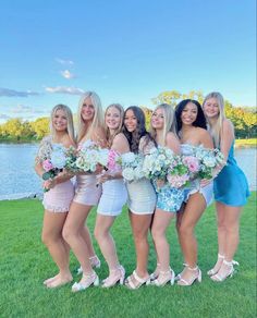 a group of women standing next to each other on top of a grass covered field