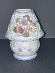 a white vase with flowers on it sitting on a table