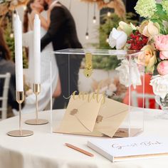 a newly married couple standing next to each other in front of a table with flowers and candles