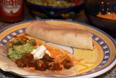 a burrito with meat, cheese and guacamole is on a plate