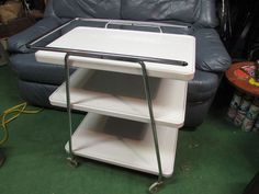 a white table sitting on top of a green carpeted floor next to a couch