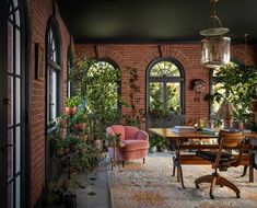 a dining room with brick walls and arched windows, potted plants on either side of the table