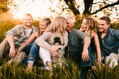 a group of people that are sitting in the grass with a dog on their lap