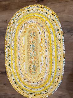 a yellow and white oval rug on top of a wooden floor next to a wall