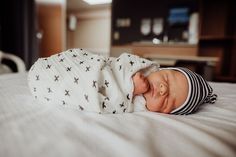 a baby wrapped in a blanket laying on top of a bed