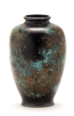 a black vase with green and brown designs on the outside, against a white background