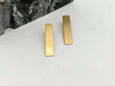 Introducing our sleek and stylish Rectangular Brass Drop Earrings - the perfect blend of minimalist elegance and timeless charm. Crafted from high-quality brass, these earrings feature a clean and contemporary design, with rectangular shapes that exude sophistication and versatility. The rich, warm tones of brass add a touch of understated luxury to any ensemble, making these earrings the ideal accessory for both casual and formal occasions. Lightweight and comfortable to wear, these drop earrings effortlessly transition from day to night, adding a subtle yet striking accent to your look. Whether you're dressing up for a night out or adding a touch of polish to your everyday style, these earrings are sure to become a staple in your jewelry collection. With their classic silhouette and refi Minimalist Linear Earrings For Formal Occasions, Everyday Modern Rectangular Linear Earrings, Gold Rectangular Linear Earrings For Everyday, Modern Rectangular Pendant Earrings As Gift, Minimalist Oblong Earrings For Formal Occasions, Classic Rectangular Earrings For Everyday, Formal Minimalist Oblong Earrings, Gold Rectangular Everyday Earrings, Contemporary Rectangular Earrings For Gift