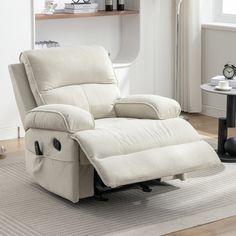 a white recliner sitting on top of a rug in a living room next to a table