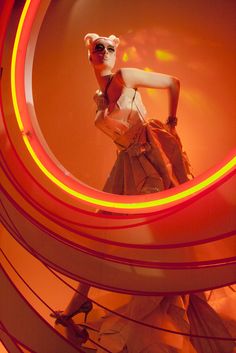 a mannequin dressed in an orange dress with red and yellow lights around her