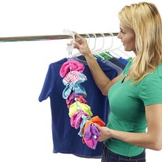 a woman is looking at clothes hanging on a rack and holding a t - shirt