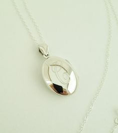 "This sterling silver locket necklace makes a beautiful present for any mother, grandmother, friend or loved one.. I will engrave an Initial onto the small oval locket which holds two photos. Pendants and necklace are sterling silver. Hangs from a long 30\" sterling silver chain. Locket- sterling silver Necklace- 30\" long, sterling silver How to Order: 1. Place item or items in cart. (If purchasing more than one item the shipping will automatically be combined. For 5 or more items, contact me f Cheap Nickel-free Locket Necklace For Keepsake, Luxury Engraved Sterling Silver Locket Necklace, Elegant Locket Necklace With Hallmark For Mother's Day, Elegant Medallion Locket Necklace For Personalized Gift, Silver Oval Pendant For Personalized Gift, Silver Oval Pendant Jewelry For Personalized Gift, Elegant Medallion Locket Necklace For Mother's Day, Elegant Keepsake Jewelry With Initials, Classic Locket Necklace Gift