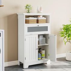 a white cabinet with baskets and towels on it next to a washer dryer