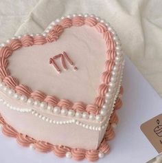 a heart - shaped cake with pearls and pink icing is on a white tablecloth