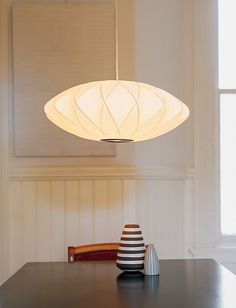 a table with a vase and lamp on it in front of a white paneled wall