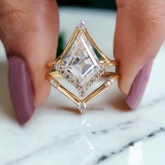 a woman's hand holding an engagement ring with a large white diamond in the center