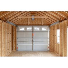 the inside of a garage that is being built with wood paneling and two windows