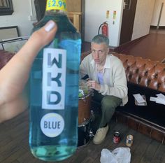 a man sitting on a couch with a bottle of blue liquid in front of him