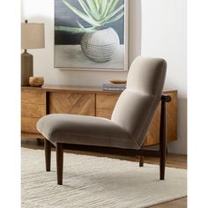 a chair sitting on top of a rug in front of a table with a painting above it